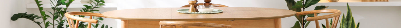 Extending oak dining table shown in a bright dining room with wooden chairs and natural décor.